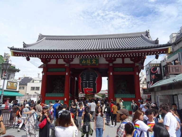 Grande lanterna vermelha no portão Kaminarimon, em Asakusa, com visitantes na entrada.