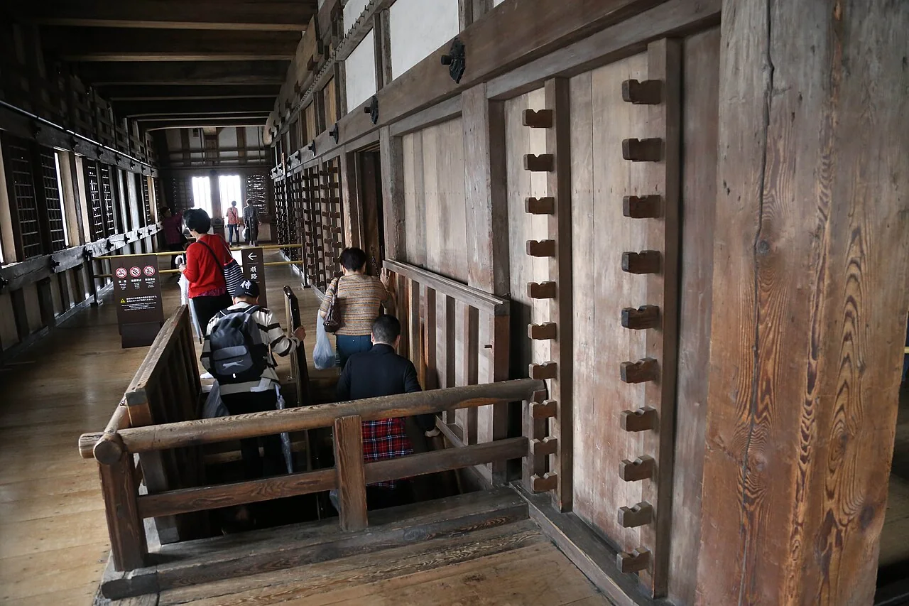 Visitantes em área de circulação de madeira com desnível dentro do Castelo de Himeji.