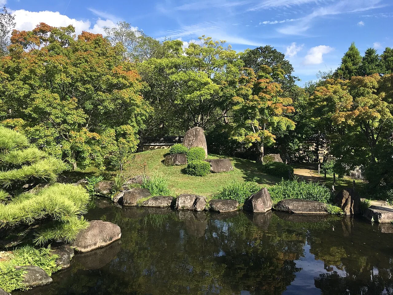 Lago com pedras e vegetação no jardim Tsukiyama Chisen, em Koko-en.