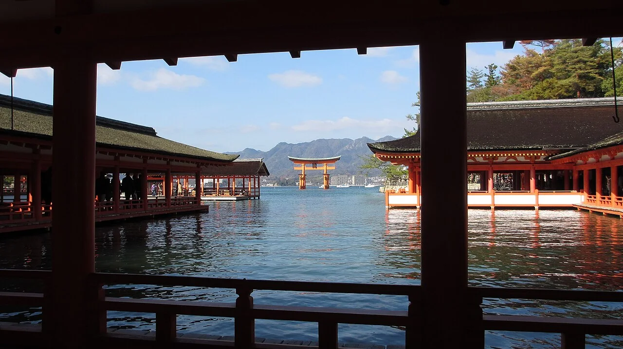 Corredores do Santuário Itsukushima cercados por água, com o grande torii ao fundo.