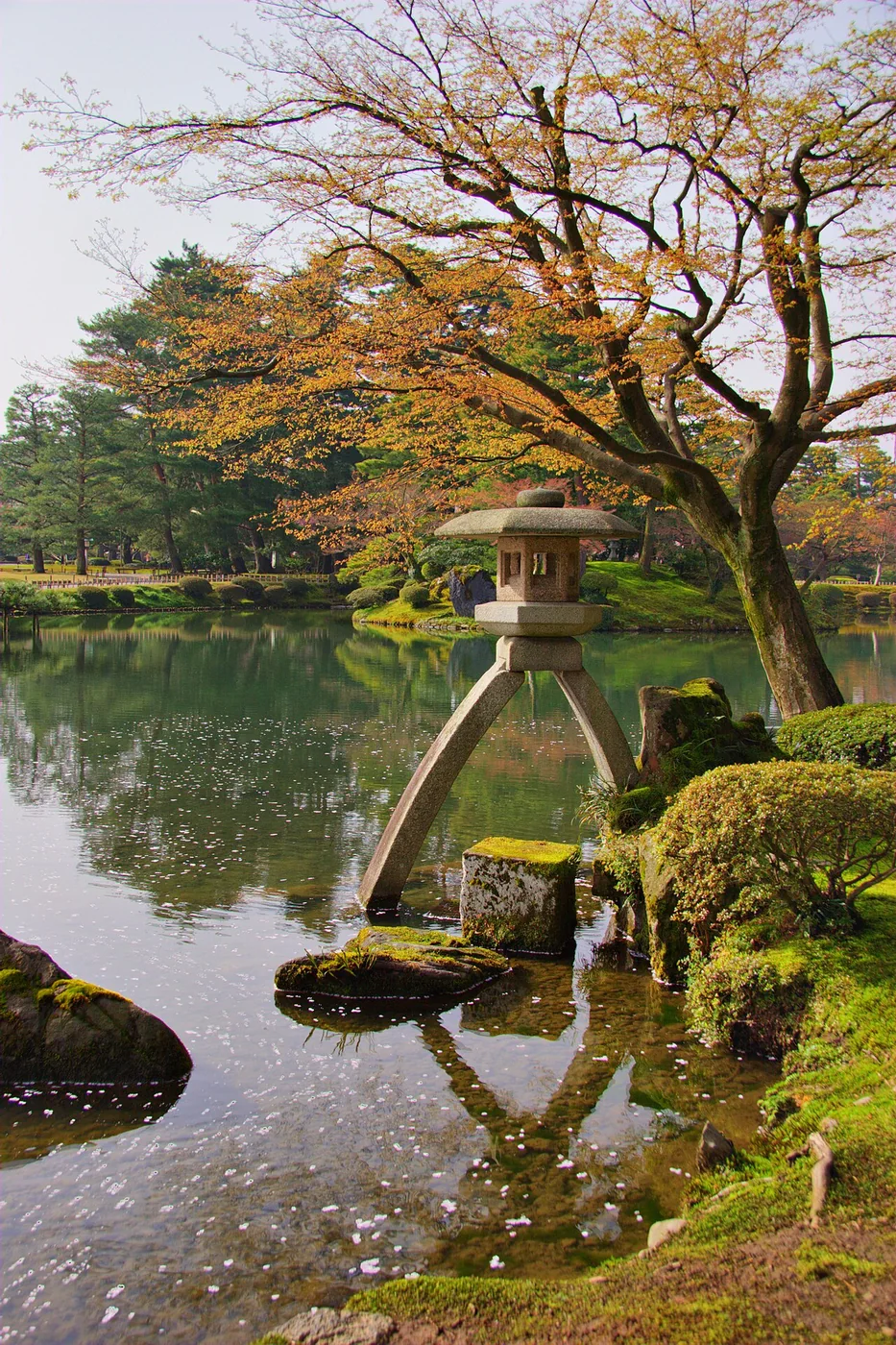 Lanterna de pedra Kotoji junto ao lago e às árvores do jardim Kenrokuen, em Kanazawa.