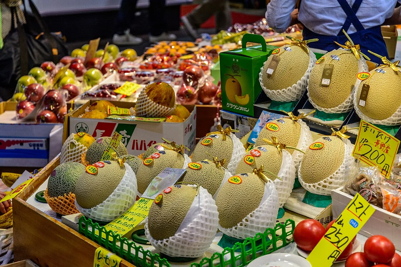 Banca de frutas com melões e placas de preço no mercado Omicho, em Kanazawa.