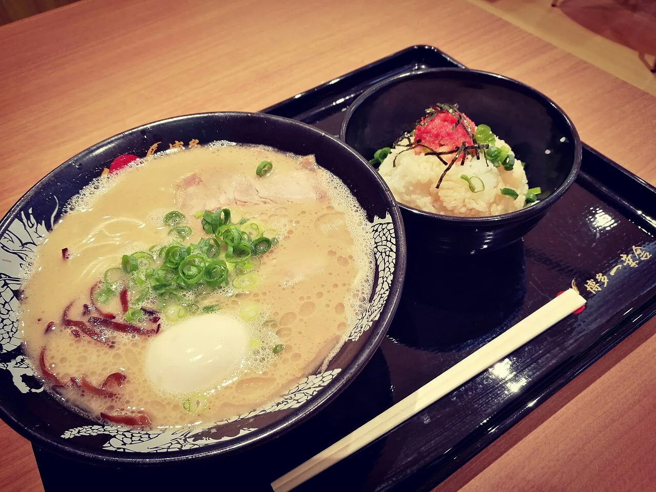 Tigela de Hakata ramen com caldo claro e cremoso, cebolinha e acompanhamentos.