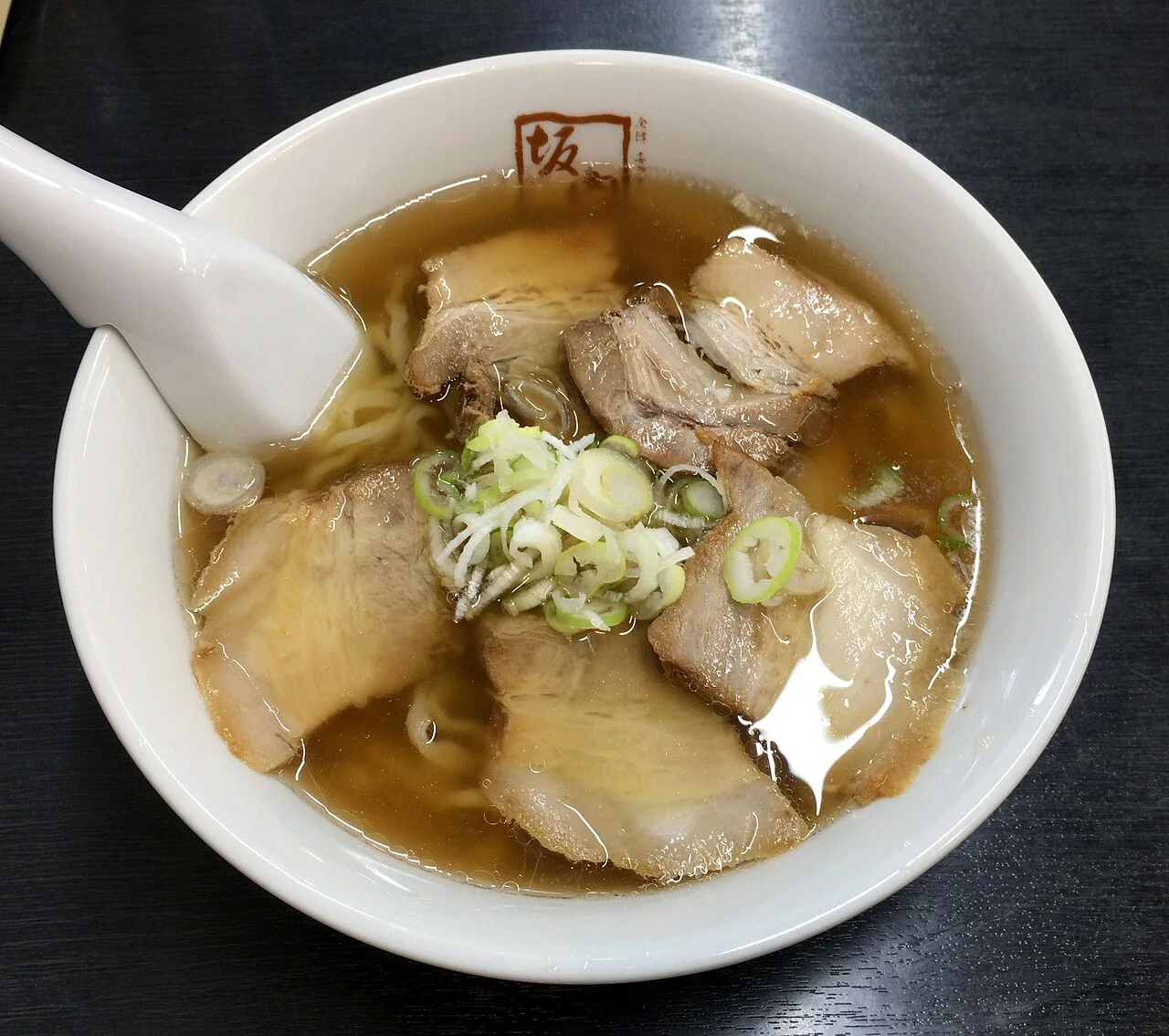 Tigela de Kitakata ramen com fatias de carne, cebolinha e caldo claro.