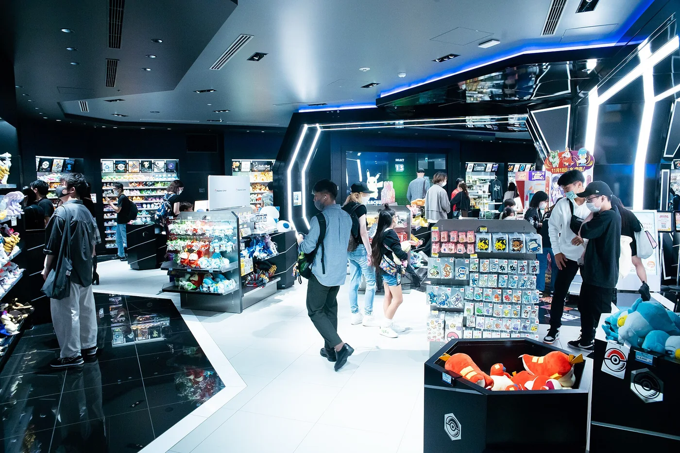 Interior do Pokémon Center Shibuya, com expositores de produtos e visitantes.