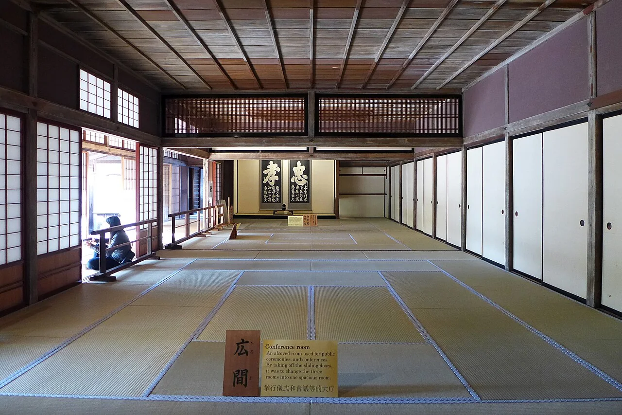 Sala com piso de tatame, pilares de madeira e painéis claros no Takayama Jinya.