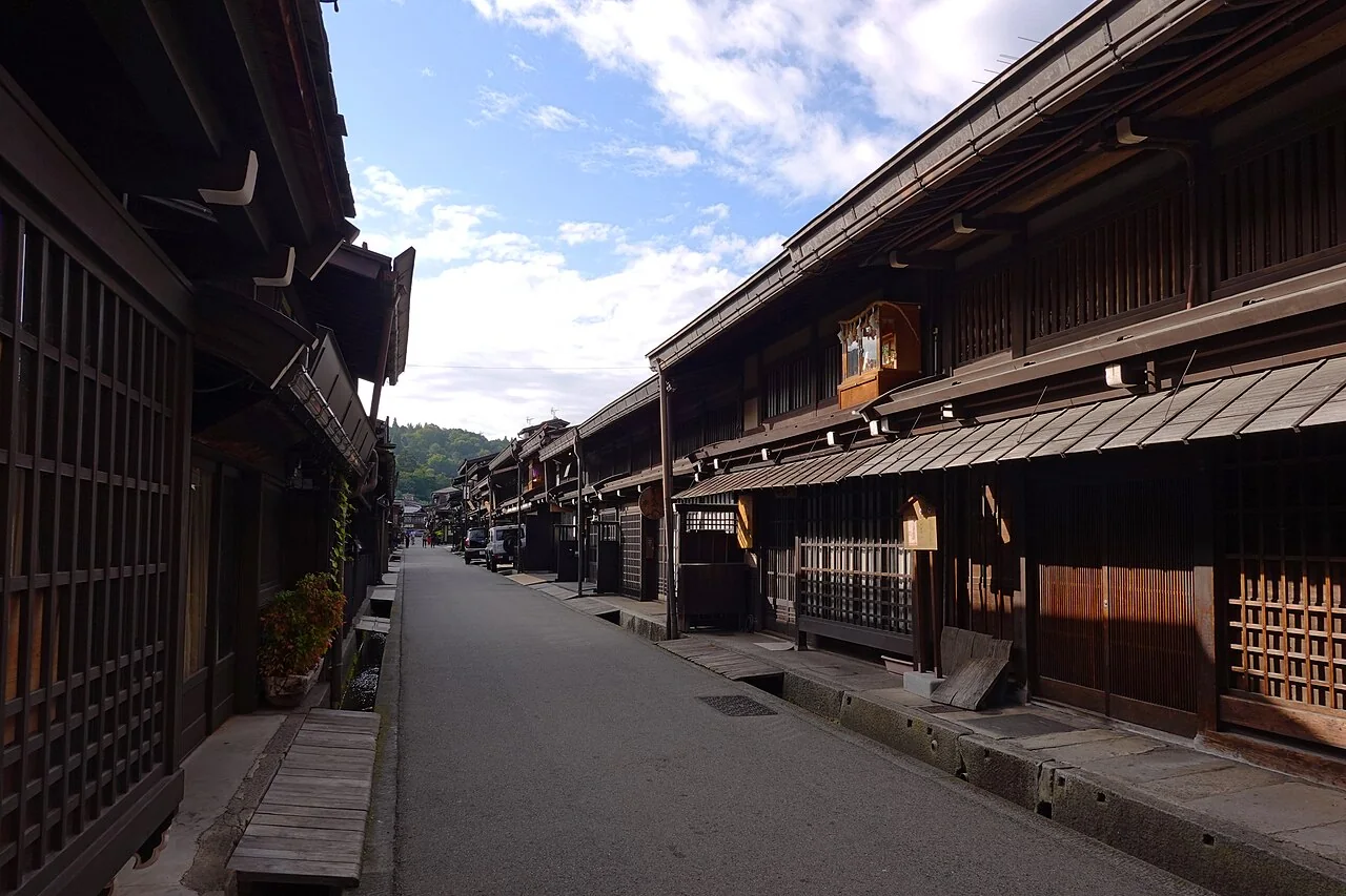 Rua de Sanmachi com casas de madeira escura e visitantes em Takayama.