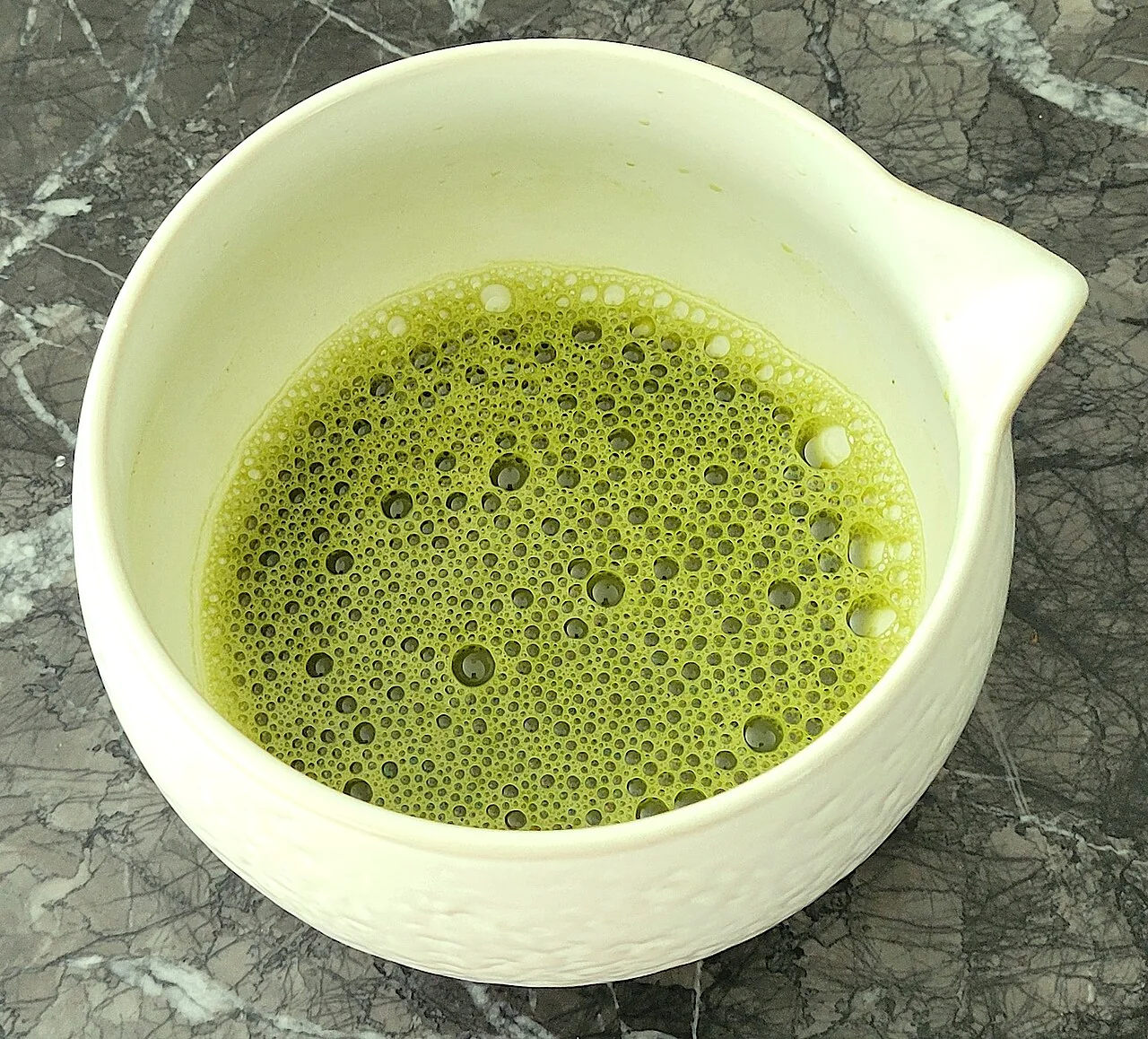 Matcha preparado em uma tigela clara, visto de cima.